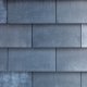 Detaljfoto av fasadekledning på Malmøgata. Mørke fasadeplater er lagt med overlapp. Spill i fargen får fasadekledningen til å minne om steinheller.