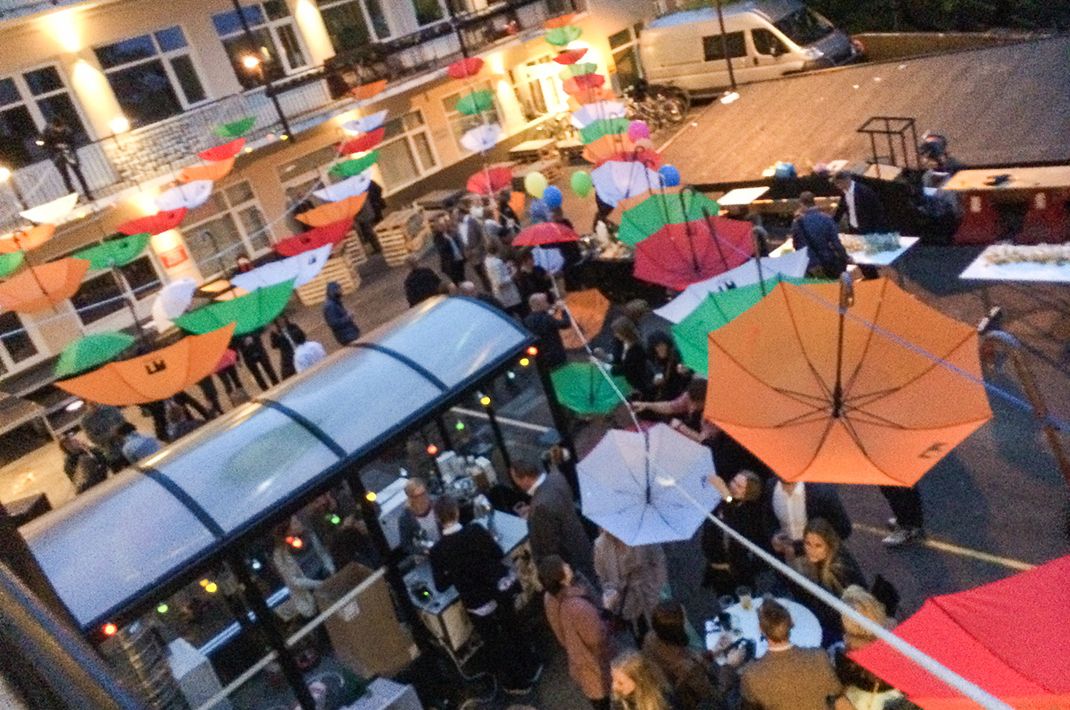 De dekorative paraplyene senkes ned slik at folk får beskyttet seg mot regnværet på kvelden